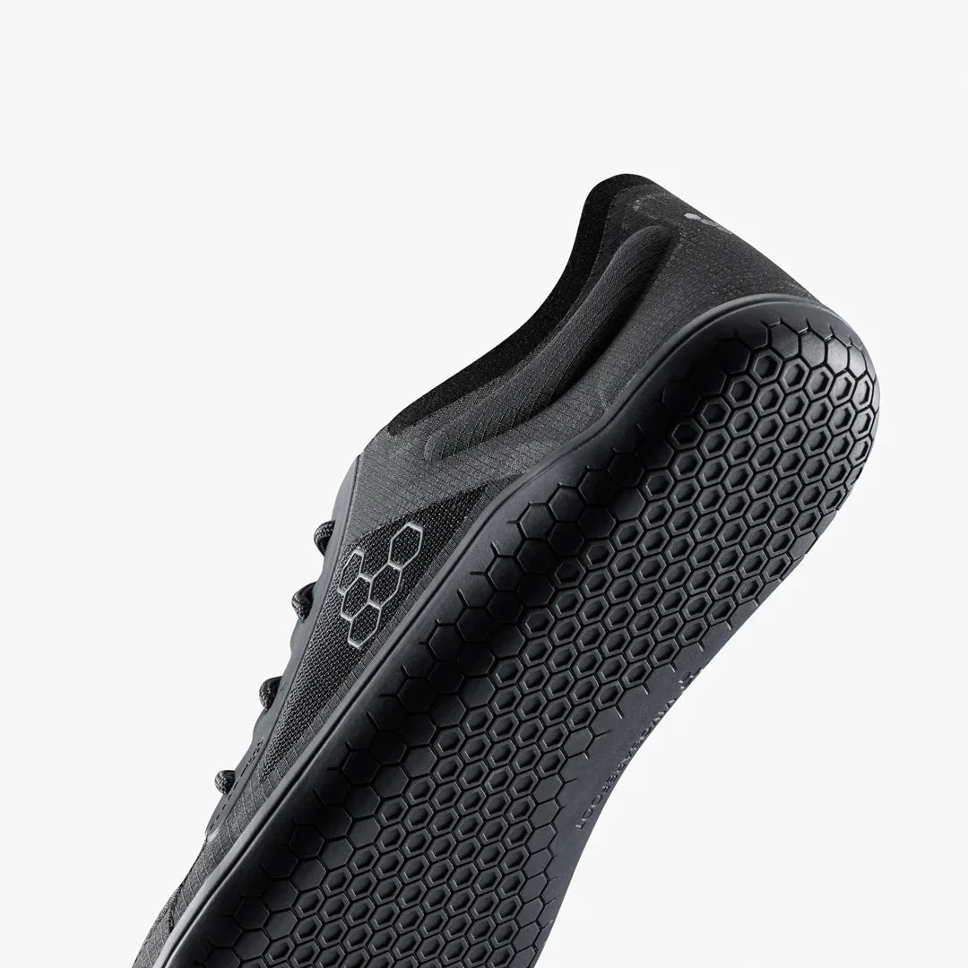 Black athletic shoe with textured sole on a white background