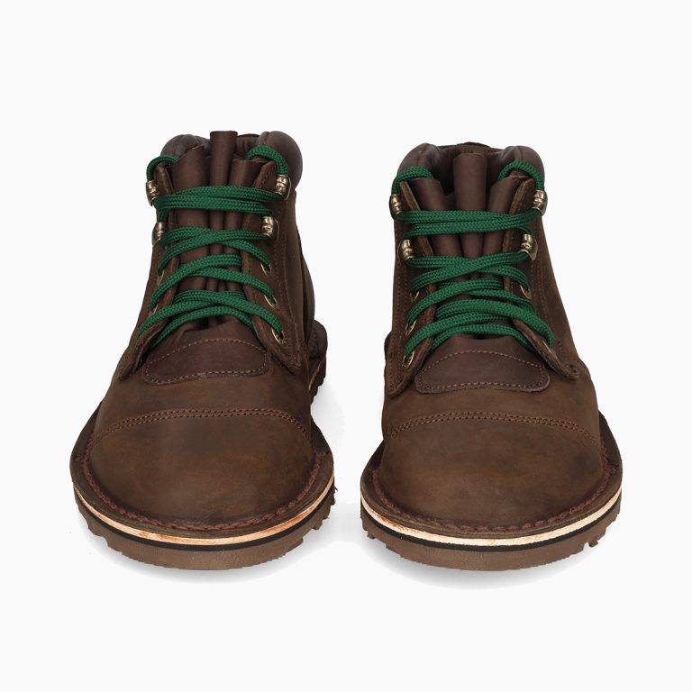 Pair of brown leather boots with green laces on a white background