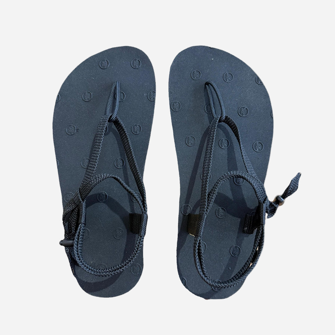 Pair of navy blue sandals with black straps on a white background