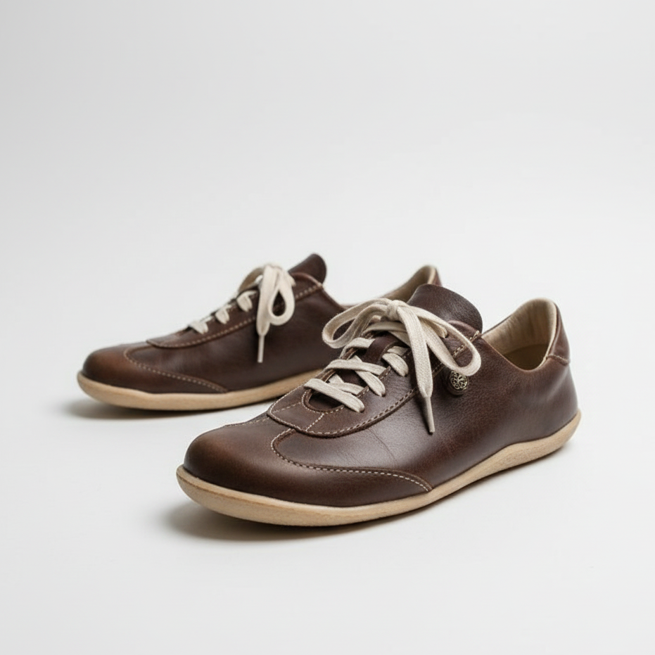 Pair of brown leather shoes with white laces on a light gray background