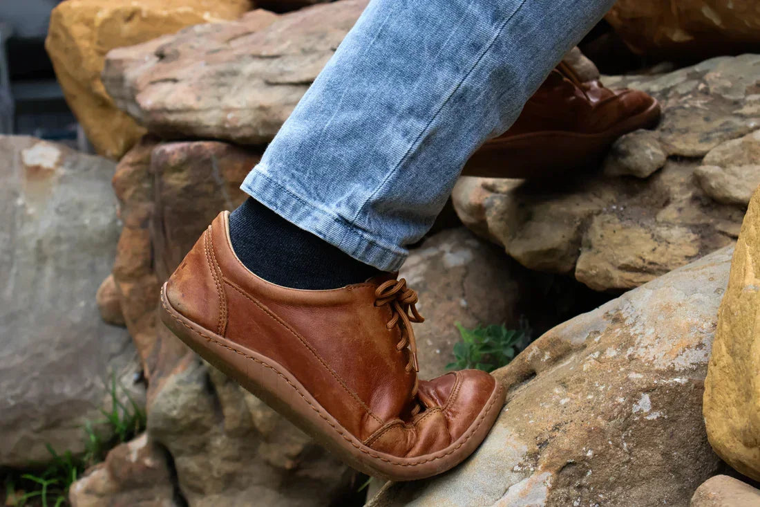 Brown leather shoes and blue jeans on a rocky surface
