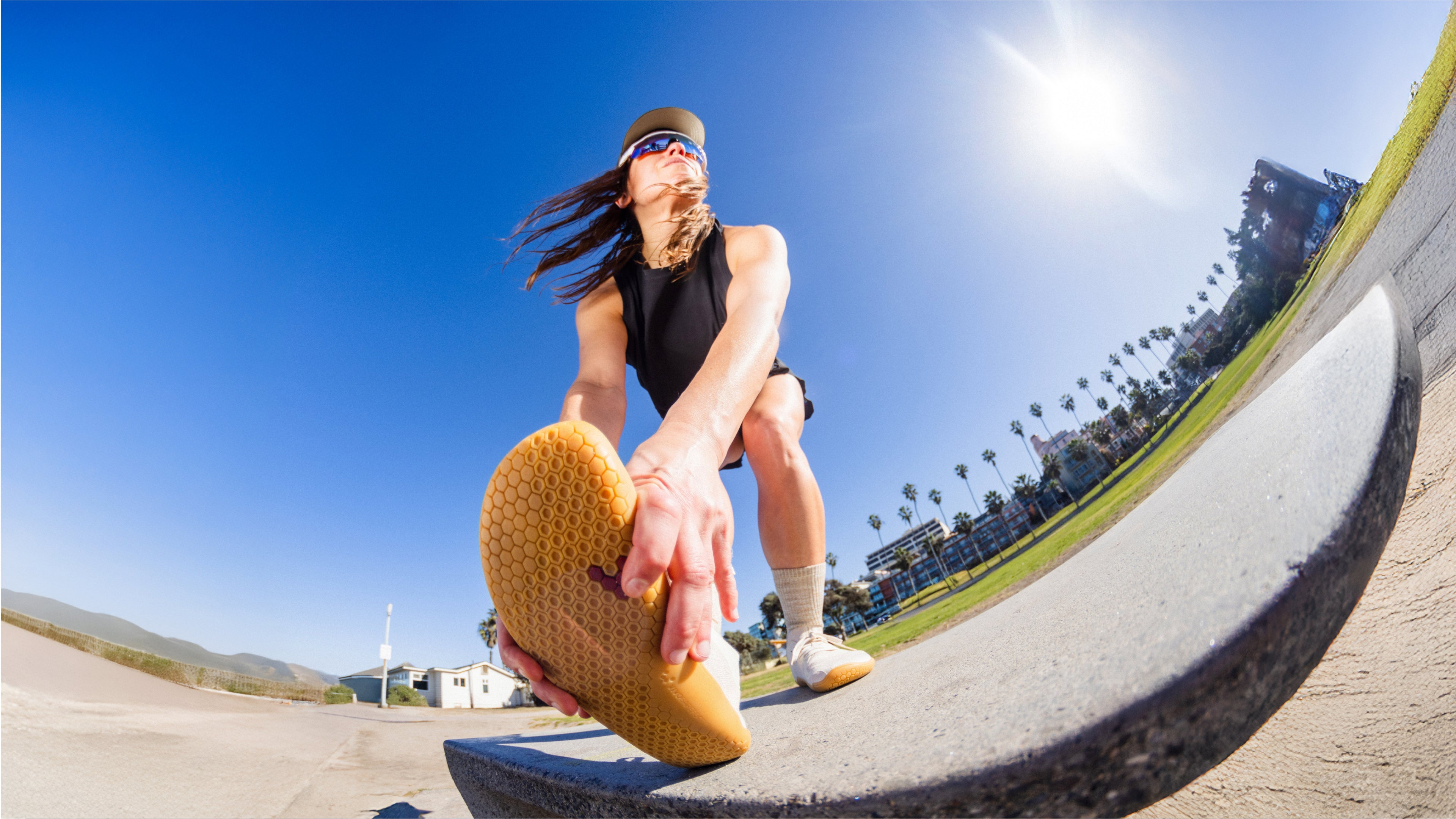 Person skateboarding on a concrete ledge with palm trees and buildings in the background