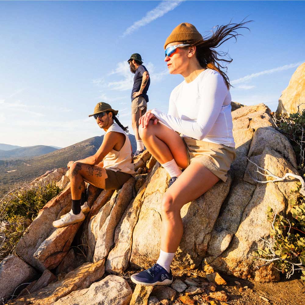 Two people sitting on rocks with a scenic mountain view in the background